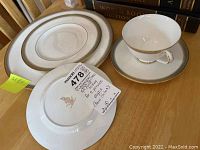 Photo showing a place setting including cup, saucer, salad plate, and bread plate with note describing the set as Royal Doulton Clarendon five-piece place settings for 12 persons, total 60 pieces bone china.
