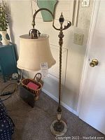 Full view of the antique floor lamp placed beside a door showing height and overall condition.