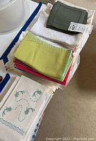 Stack of assorted cloth napkins and linens showing solid color napkins and white lace-edged linens