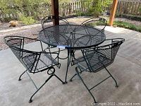 Full set shot under covered patio showing table and all four chairs