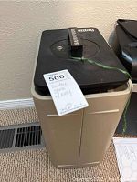 Full view of the Sentry safe showing beige body and black top with key tied by green string.