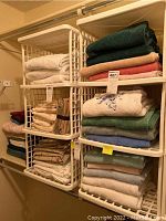 Two sets of white plastic stacking cubes holding folded towels and linens (contents not included) shown from front view