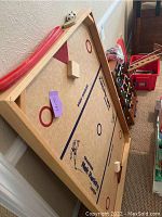 Top angled view of the Champion Nick Hockey tabletop hockey game on the floor showing playing surface, wooden frame, paddles, and puck.