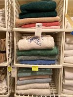 Stack of 14 assorted towels in various colors, folded and placed on metal shelving unit.