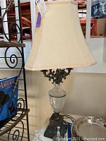 Full view of the vintage table lamp including its silk lamp shade and part of the nearby items