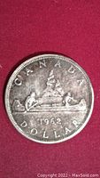 Front side of 1962 Canada silver dollar coin showing canoe design.
