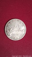 Close-up image of the 1965 Canadian silver dollar coin showing the voyageur design, date, and surrounding text.