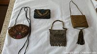 All four vintage beaded purses and clutches laid out on a white cloth background, showing relative sizes and styles.