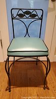 Front view of metal chair with turquoise vinyl padded seat, showing the design and seat cushion.