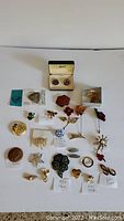 Full assortment of jewelry items including pins and the Breco cufflinks boxed set on white background.