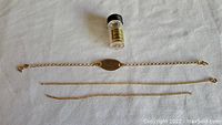 All three chain pieces laid flat with vial in top center