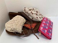 Photo showing all five items together: brown vegan handbag, cream coin purse, white ladybug scarf, red beaded butterfly evening bag, and pink flamingo wallet.