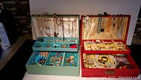 Two open jewelry boxes filled with an assortment of necklaces, bracelets, earrings, pins, brooches, rings, and other jewelry pieces.