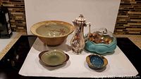 All items displayed together on a cloth background showing overall lot contents including teapot, bowls, flower frog and ashtray.