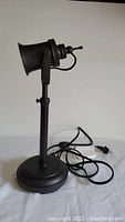 Side profile of railroad light style table lamp showing the adjustable head and cord with switch.