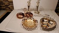 Full view of all items showing candlesticks, dual bon bon server, footed dish, leaf shaped dish and tongs