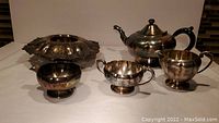 Silverplate teapot, sugar bowl, creamer, and flower frog holder side by side showing shapes and size.