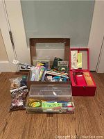 Lot contents showing the sewing machine case, plastic boxes with thread, needles, tape measure, buttons, and other crafting tools
