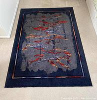 Full view of New Zealand wool rug with dark blue border and abstract multicolored interior design.