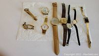 Overview of nine wristwatches on paper towel, various brands and styles