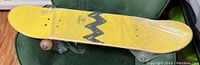 Side view of the yellow top deck with black zigzag pattern wrapped in protective plastic.