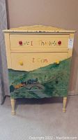 Front view of child's painted chest of drawers showing two drawers, painted train scene and 'I Think I Can' text.
