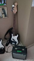 Bass guitar leaning against wall with amplifier on carpet.