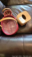 Top view of the two Longaberger baskets with their fabric liners and the wooden tissue box cover on a leather surface.