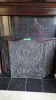 Front view of the bi-fold fireplace screen showing scrollwork and mesh design
