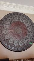 Front view of large round floral wall hanging showing detailed petal design and decorative borders in metallic finish.