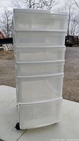 Front view of the white 6 drawer plastic storage cabinet with casters outdoors.