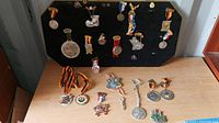 Overall view of German pins and medals secured on the black pin board and additional pieces placed on the table beneath it