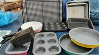 Overview of various baking pans, muffin tins, and colorful round pans including wire rack