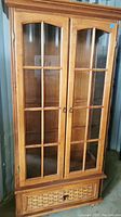 Front view of the wooden display cabinet showing two glass doors and lower drawer.