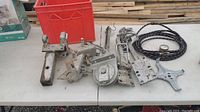 Multiple metal trailer sway bar attachment parts arranged on a table including brackets, shackles, and bolts.