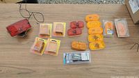 Overview of assortment of trailer light parts including red and amber lights, reflectors, and packaged items on wooden table