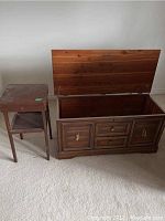 Photo showing the wooden chest with lid open and the wooden stand beside it, both with visible scratches and wear.
