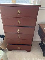 Front view of wood 6 drawer cabinet with metal ring handles, drawers slightly open, scratches visible