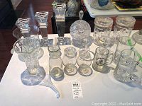 Full set of glassware items including candle holders, mugs, canisters, decanter, candy bowl, and funnel arranged on table