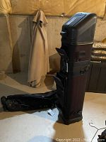 Upright hard shell travel case showing overall shape, fabric lower section and attached pockets