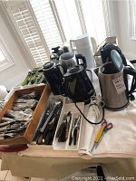 Wide view showing electric kettles, cutlery in trays and wooden box, and small kitchen appliances behind