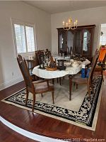 Wool rug displayed under wooden dining table set to show size and style in home setting.