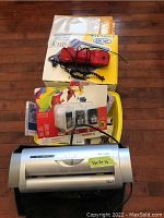 Shredder, phones, printer ink cartridges, VHS tapes, and paper items arranged on floor.