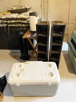 Photo showing the folding wood table, white and gray cooler with cup holders, two black wooden CD stands, and black Ionicpro air cleaner tower.