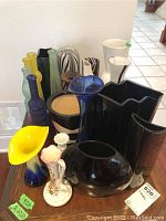 Photo showing assortment of fourteen vases and five frosted bottles including colors of black, blue, yellow, purple, and white.