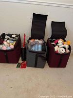 Three large zippered bags filled with assorted yarn in various colors and textures, positioned side-by-side on the floor.