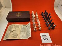 Overall view of set showing purple and pink marbled chess pieces arranged in rows alongside the vintage brown box and printed rules sheet on red background.