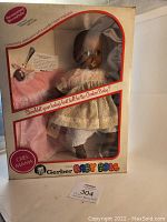 Full view of boxed 1979 Gerber Baby Doll showing doll inside with lace dress and pacifier mouth, original box with red trim and promotional text.