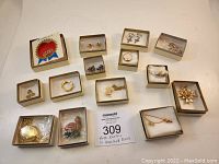 Lot of Avon jewelry in their boxes showing multiple earrings, rings, brooches, pendants and a tie pin.