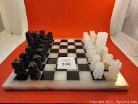 Full frontal view of the Aztec style black and white onyx chess set with pieces arranged on board.